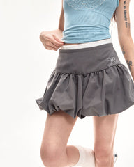 A coquette aesthetic grey mini skirt with a high-waist design and voluminous, pleated structure. The skirt features a puffy silhouette with a bubble hem for a unique look
