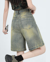 These high-waisted denim shorts feature a faded wash with distinct color gradations and a knee-length cut. They have a front zip closure, belt loops, and a classic five-pocket design