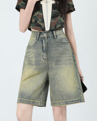 These high-waisted denim shorts feature a faded wash with distinct color gradations and a knee-length cut. They have a front zip closure, belt loops, and a classic five-pocket design