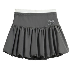 A coquette aesthetic grey mini skirt with a high-waist design and voluminous, pleated structure. The skirt features a puffy silhouette with a bubble hem for a unique look